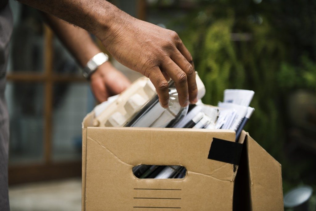 person piling up things to recycle in a box