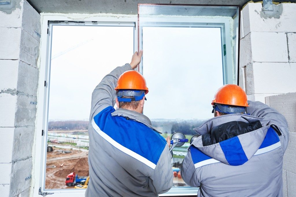 male industrial builders worker at window installation in building construction site