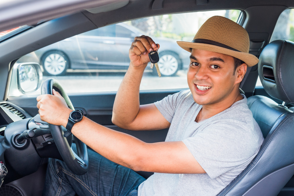 man with car keys in driver's seat brand new car